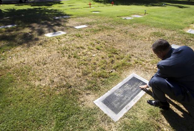 James Mullikin, managing partner of Bunkers Mortuaries, Cemeteries & Crematory, brushes grass off the headstone of former Las Vegas Mayor William "Bill" Briare and Leona Jo Briare at Woodlawn Cemetery Thursday, Aug. 8, 2013. Briare was the mayor of Las Vegas from 1975 to 1987.