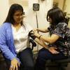 In this photo taken Thursday, April 11, 2013 Liz DeRouen, 49, left, gets her blood pressure checked by medical assistant Jacklyn Stra, right, at the Sonoma County Indian Health Project in Santa Rosa, Calif. 