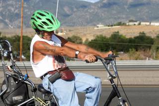 In this Aug. 8, 2013 photo, Glenn Lucky rides north on Highway 395 near Sunridge, Nev. At 60, Lucky has slowed just a little, friends say, but his tanned arms remain chiseled by his near-daily bicycle rides between Indian Hills and downtown Carson City.