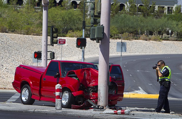 A Nevada Highway Patrol trooper takes a photo of a pickup truck at the Rampart Boulevard and the Summerlin Parkway eastbound onramp Tuesday, Aug. 20, 2013. The driver was critically injured in the single-vehicle accident, according to NHP. 