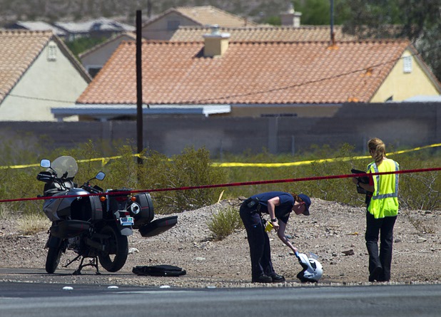 A crime scene analyst looks over motorcycle helmet as Henderson Police investigate an officer-involved shooting near Boulder Highway and College Drive in Henderson, Aug. 20, 2013.  
