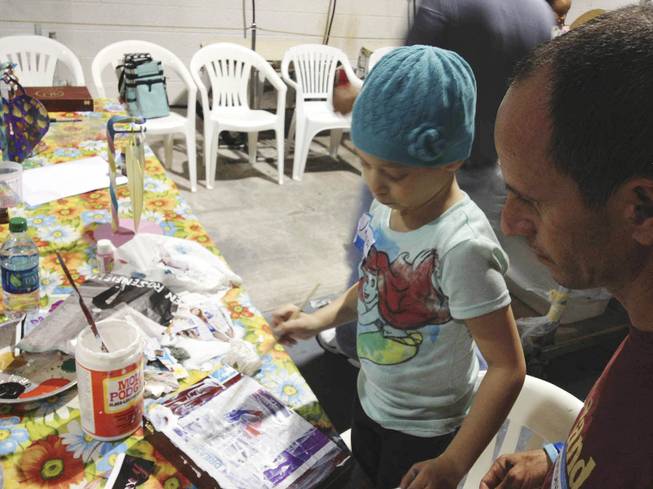 Junaisy Vargas, 5, paints a box with her father, Otoniel Vargas, at Kaiden Bresgi-Goffard's 11th birthday on Saturday, Aug. 23, 2013. Junaisy recently completed chemotherapy for a tumor and is in the Cure 4 the Kids program, which helps children with genetic disorders and rare illnesses. 
