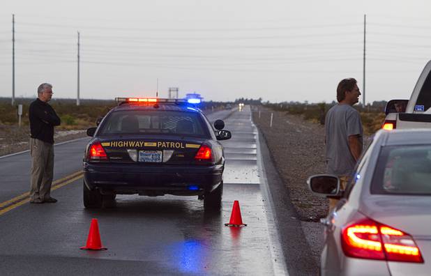A man talks with a Nevada Highway Patrol trooper as he waits for Kyle Canyon Road to reopen Sunday, Aug. 25, 2013.
