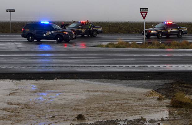 Nevada Highway Patrol Troopers confer on U.S. 95 after the highway was closed in both directions due to flooding near Kyle Canyon Road Sunday, Aug. 25, 2013.