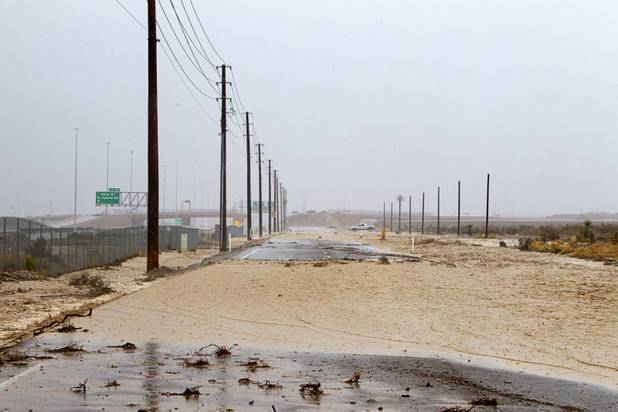 Storm runoff flows over the roadway near U.S.95 near Horse Drive Sunday, Aug. 25, 2013.