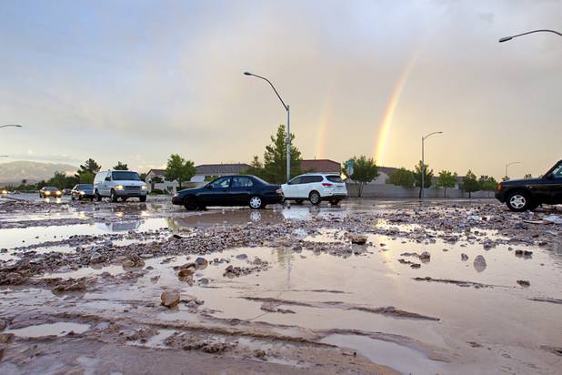 Vehicles pass through an intersection full of storm runoff and debris at El Capitan Way and Racel Street after a thunderstorm in the northwest part of the Valley Sunday, Aug. 25, 2013. 