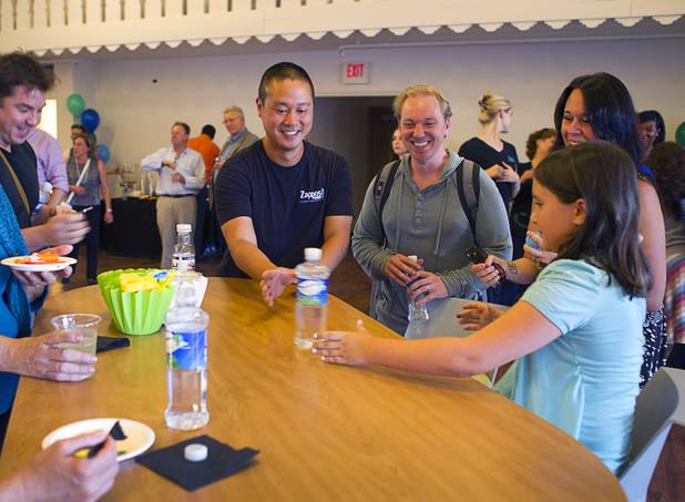 Zappos CEO Tony Hsieh, center, slides a water bottle to Chloe Buck, 8, as they wait for a grand opening ceremony to start at the 9th Bridge School in downtown Las Vegas Tuesday, Aug. 27, 2013. The private school/early childhood learning center, part of the Downtown Project, opened August 26 with infants through kindergarten students and will gradually add grades.