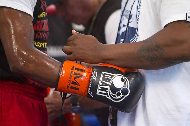 Undefeated boxer Floyd Mayweather Jr. gets help removing his gloves during a workout at the Mayweather Boxing Club Wednesday, August 28, 2013. Mayweather will face Canelo Alvarez of Mexico in a WBC/WBA 154-pound title fight at the MGM Grand Garden Arena on September 14.