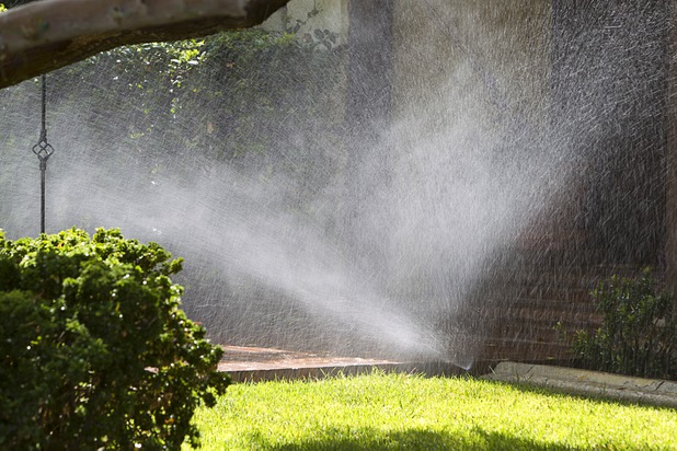 A sprinkler waters a lawn at a home near Rancho Drive and Oakey Boulevard Aug. 29, 2013. The lawn sprinklers were running at a prohibited time and overwatering so that water flowed into the gutter.