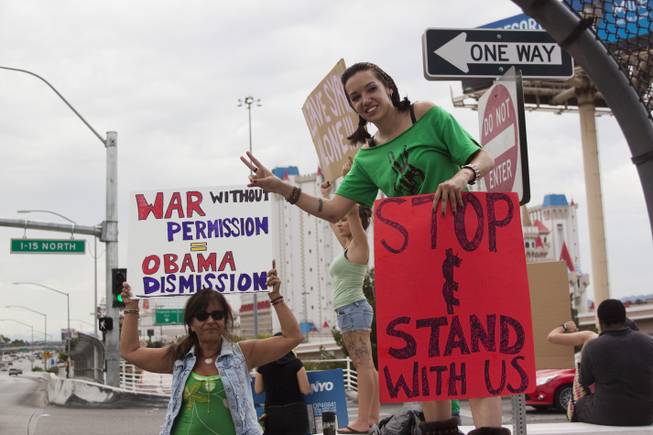 People hold up peace and anti-war signs during a protest against U.S. intervention in Syria held on Tropicana and the I-15, Saturday, Aug. 31, 2013.