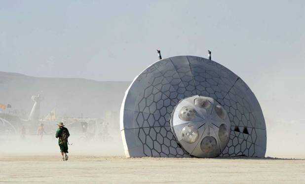 In this Thursday, Aug. 29, 2013 photo, a man walks past an art piece at Burning Man in Gerlach, Nev. Once a year, tens of thousands of participants gather for Burning Man in Nevada's Black Rock Desert to create Black Rock City, dedicated to community, art, self-expression and self-reliance.
