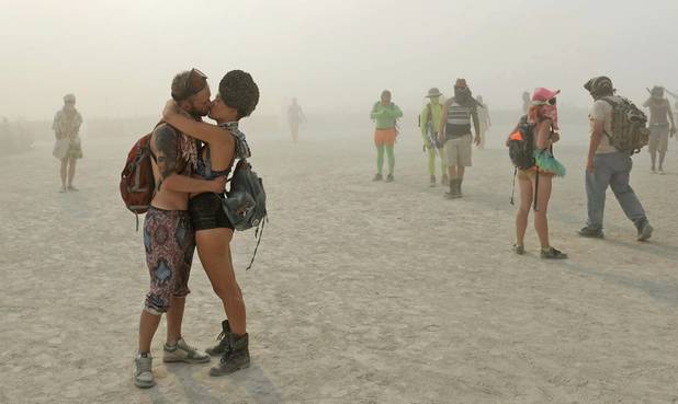 In this Wednesday, Aug. 28, 2013 photo, a couple kisses at Burning Man in Gerlach, Nev. Once a year, tens of thousands of participants gather in Nevada's Black Rock Desert to create Black Rock City, dedicated to community, art, self-expression and self-reliance. 