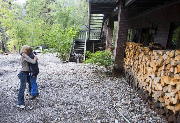 Becky Grismanauskas, right, gets a hug from fellow resident Lauren Olson after heavy storm runoff tore through the Rainbow Canyon subdivision on Mount Charleston Sunday, Sept. 1, 2013.