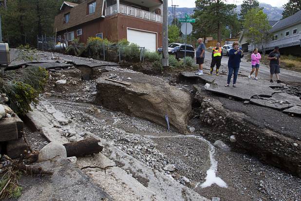Residents take photos of damage to Rainbow Canyon Boulevard after heavy storm runoff tore through the Rainbow Canyon subdivision on Mount Charleston Sunday, Sept. 1, 2013.