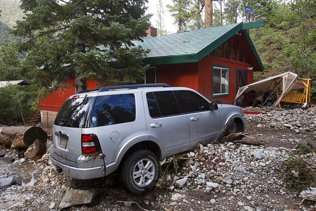 A SUV is shown outside a home after heavy storm runoff tore through the Rainbow Canyon subdivision on Mount Charleston Sunday, Sept. 1, 2013.