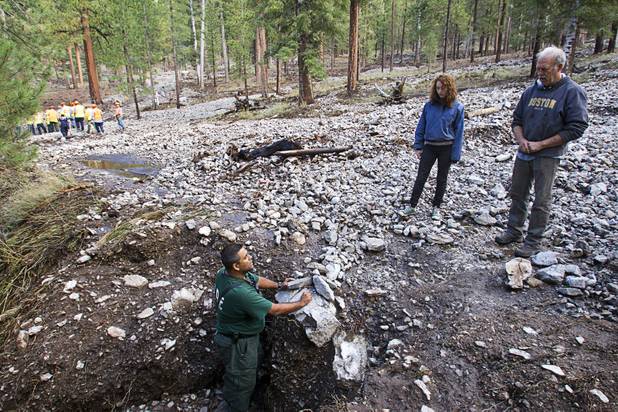 Nevada Division of Forestry firefighter Jorge Gonzalez, left, talks with resident Mike McDonald and his daughter Maggie after heavy storm runoff tore through the Rainbow Canyon subdivision on Mount Charleston Sunday, Sept. 1, 2013.
