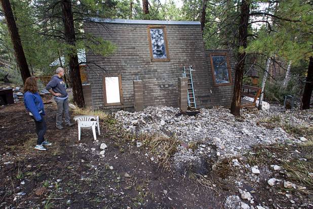 Resident Mike McDonald and his daughter Maggie look at rocks piled against their cabin after heavy storm runoff tore through the Rainbow Canyon subdivision on Mount Charleston Sunday, Sept. 1, 2013. "You could see under the house before, " McDonald said.