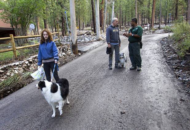 Nevada Division of Forestry firefighter Jorge Gonzalez, right, talks with resident Mike McDonald after heavy storm runoff tore through the Rainbow Canyon subdivision on Mount Charleston Sunday, Sept. 1, 2013. McDonald and his daughter Maggie decided to leave with their dogs and got a ride into town.