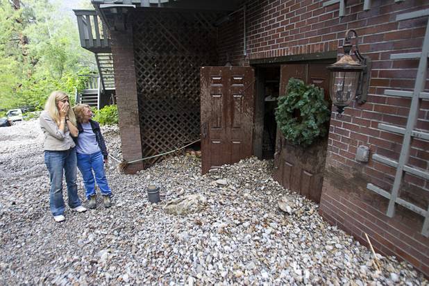 Lauren Olson, left, and Becky Grismanauskas, right, look over damage to the Grismanauskas home after heavy storm runoff tore through the Rainbow Canyon subdivision on Mount Charleston Sunday, Sept. 1, 2013.