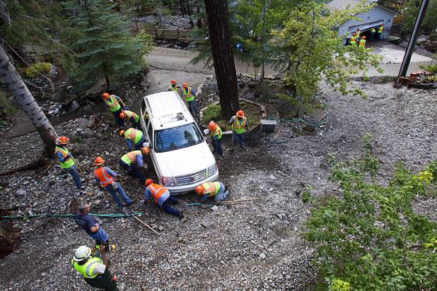 A crew works to dig out an SUV after heavy storm runoff tore through the Rainbow Canyon subdivision on Mount Charleston Sunday, Sept. 1, 2013.