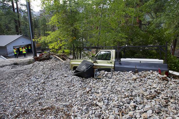A pickup is shown partially buried in rocks after heavy storm runoff tore through the Rainbow Canyon subdivision on Mount Charleston Sunday, Sept. 1, 2013.