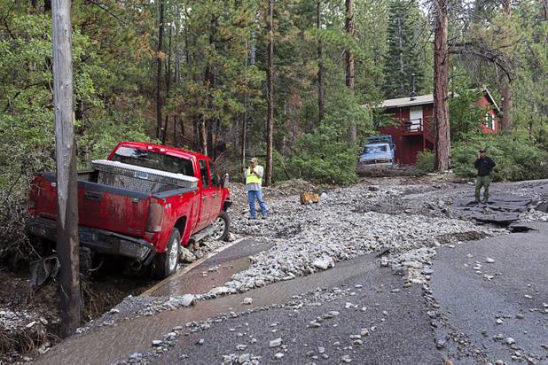 A man takes a photo of a pickup truck that was swept away by heavy storm runoff in the Rainbow Canyon subdivision on Mount Charleston Sunday, Sept. 1, 2013.
