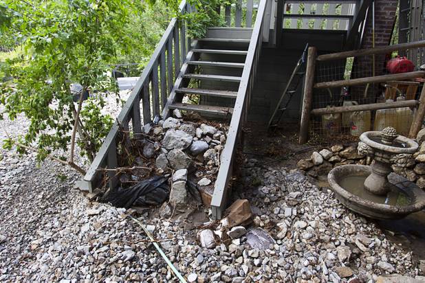Rocks and debris are piled up along a home after heavy storm runoff tore through the Rainbow Canyon subdivision on Mount Charleston Sunday, Sept. 1, 2013.