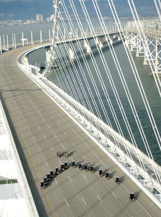 In this photo taken on Monday, Sept. 2, 2013, provided by the Bay Area Toll Authority, a phalanx of police officers cross the San Francisco-Oakland Bay Bridge after leading a procession marking the east span's opening, in San Francisco. At the modest inaugural ceremony, the new, self-anchored suspension bridge with its looming, single white tower was praised as a dramatic safety upgrade over its predecessor. It also was held up as a beautiful example of public art.