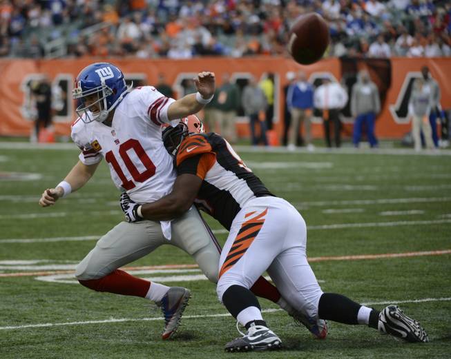 New York Giants quarterback Eli Manning (10) is pursued by Cincinnati Bengals defensive tackle Geno Atkins in the second half of an NFL football game, Sunday, Nov. 11, 2012, in Cincinnati. 
