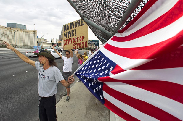 Paulo Cavalcanti, left, and Marcus Shepherd, center, express their opposition to proposed U.S. military action in Syria during a protest at the Tropicana Avenue overpass above I-15 Saturday, Sept. 7, 2013. Cavalcanti said the American flag was hung upside down as a distress signal.