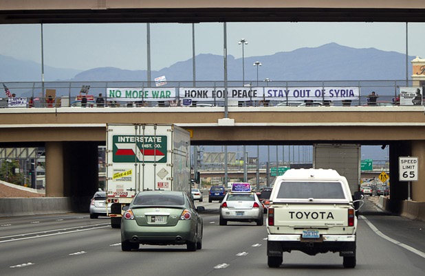 People express their opposition to proposed U.S. military action in Syria during a protest at the Tropicana Avenue overpass above I-15 Saturday, Sept. 7, 2013. About 50 people attended the protest.