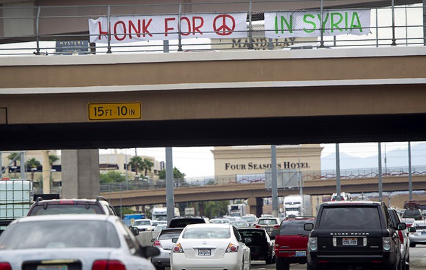 People express their opposition to proposed U.S. military action in Syria during a protest at the Tropicana Avenue overpass above I-15 Saturday, Sept. 7, 2013. About 50 people attended the protest. The photo is taken looking south.