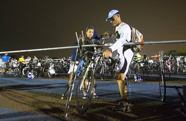 Juliette Benassi, 15, of Corsica watches as her father Dominique Benassi, 52, readies his bicycle in preparation for the Ironman 70.3 World Championship at Lake Las Vegas in Henderson Sunday, Sept. 8, 2013. Dominique has previously competed in 13 world championship races, he said. More than 1,800 athletes from around the U.S. and 53 countries qualified for the event.