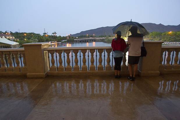 A couple takes shelter under an umbrella as they wait for the start of the Ironman 70.3 World Championship at Lake Las Vegas in Henderson Sunday, Sept. 8, 2013. More than 1,800 athletes from around the U.S. and 53 countries qualified for the event.