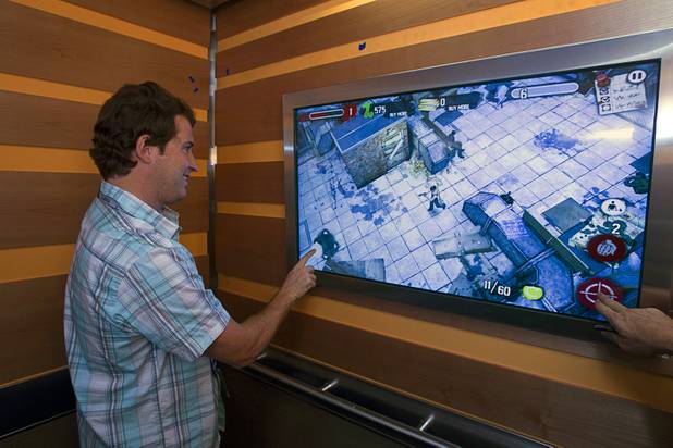 Brad Thomm, sustainability manager for Zappos, plays a video game in an elevator during a tour of the Zappos headquarters in the old city hall building downtown Monday, Sept. 9, 2013. The downtown headquarters officially opened Monday.