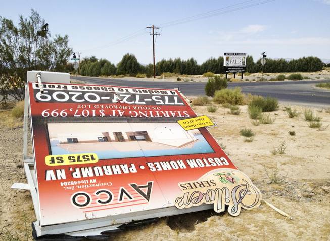 A sign in Pahrump advertising custom homes is knocked over, Monday, Sept. 9, 2013. Behind it is a sign for the master-planned community of Mountain Falls, the only place in Pahrump where subdivisions are being built.