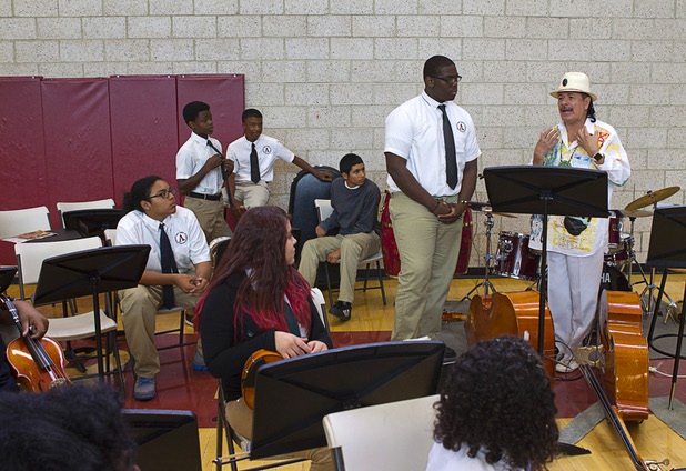Carlos Santana talks to members of the Stars Orchestra at the Andre Agassi College Preparatory Academy Tuesday, Sept. 10, 2013. Band leader Oziah Manor, 15, stand next to Santana. Santana brought a surprise donation of 200 instruments for the school's music students. The instruments came from Hermes Music, LP Music, and PRS guitars.