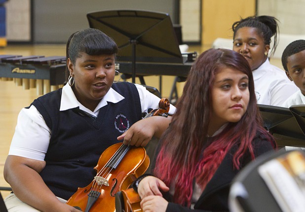 Viola players Kyla Staples, left, and Erika Enriquez listen to Carlos Santana at the Andre Agassi College Preparatory Academy Tuesday, Sept. 10, 2013. Santana brought a surprise donation of 200 instruments for the school's music students. The instruments came from Hermes Music, LP Music, and PRS guitars.