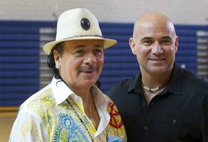 Carlos Santana stands with with Andre Agassi at Andre Agassi College Preparatory Academy on Tuesday, Sept. 10, 2013. Santana brought a surprise donation of 200 instruments for the school’s music students. The instruments came from Hermes Music, LP Music and PRS guitars.