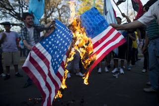 Demonstrators burn a banner that resemble US flags during a protest against a possible military attack by the United States on Syria in front of the US embassy in Buenos Aires, Argentina, Tuesday, Sept. 10, 2013. 