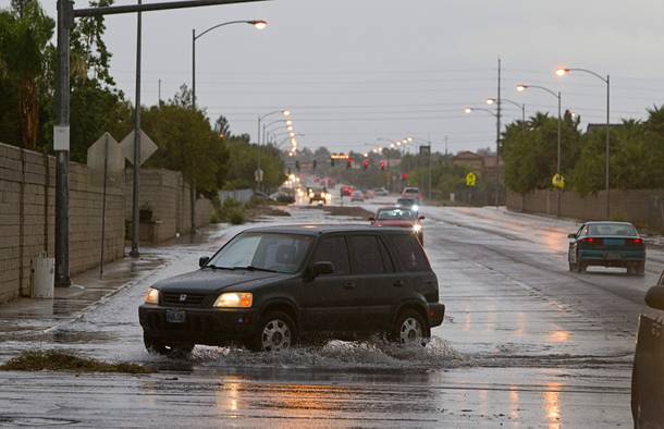 A Honda CR-V drives through storm runoff on El Capitan Way and Peace Way Wednesday, Sept. 11, 2013. 