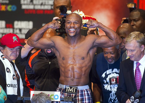 Floyd Mayweather Jr.flexes on the scale during an official weigh-in at the MGM Grand Garden Arena Friday Sept. 13, 2013. Mayweather will face Canelo Alvarez of Mexico in a WBC/WBA 154-pound title fight at the arena Saturday.