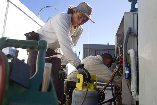 Tadone Phengrasamee, left, and Stephen Molina, HVAC technicians for the Clark County School District, work on air conditioning units at Cashman Middle School Tuesday, Sept. 17, 2013. As the effects of the recession continue to affect school operations and deferred maintenance costs continue to rise, the CCSD is finding it difficult to maintain school facilities.