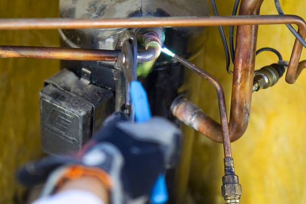 Tadone Phengrasamee, an HVAC technician for the Clark County School District, sweats a pipe as he replaces a compressor on an air conditioning unit at Cashman Middle School Tuesday, Sept. 17, 2013. As the effects of the recession continue to affect school operations and deferred maintenance costs continue to rise, the CCSD is finding it difficult to maintain school facilities.
