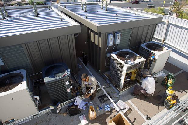 Stephen Molina, left, and Tadone Phengrasamee, HVAC technicians for the Clark County School District, work on air conditioning units on the roof of Cashman Middle School Tuesday, Sept. 17, 2013. The school, built in 1966, has about 100 individual units.