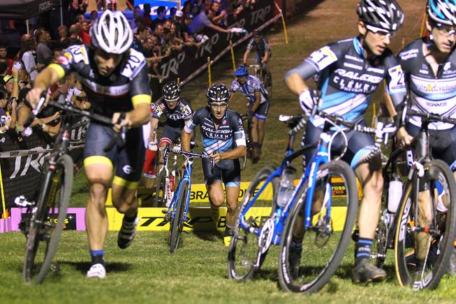 Cyclists in the elite men category charge over barriers and up a hill during the Cross Vegas cyclocross race Wednesday, Sept. 18, 2013. The race was won by two-time and current world champion Sven Nys of Belgium.