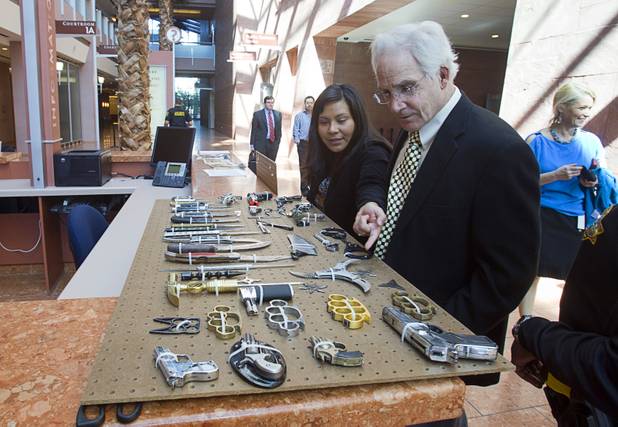 Office assistant Ingrid Gonzalez and attorney David Derrickson look over a display of confiscated weapons and prohibited items at the Regional Justice Center Thursday, September 19, 2013.