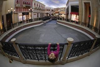 Three-year-old Luna Tasaki, of Tokyo, plays on a rail while walking along the water-drained canal with her parents at the Venetian hotel-casino, Thursday, Sept. 19, 2013, in Las Vegas. Management has closed the waterways for several weeks for maintenance.