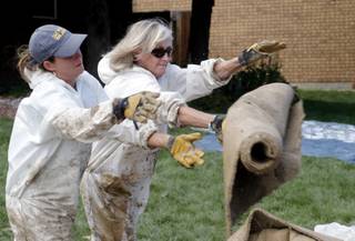 Volunteers Shawna English, left, and Sabrina Naftel throw a piece of wet carpet onto a trash pile as they help clean up a home in Longmont, Colo., on Thursday, Sept. 19, 2013. 