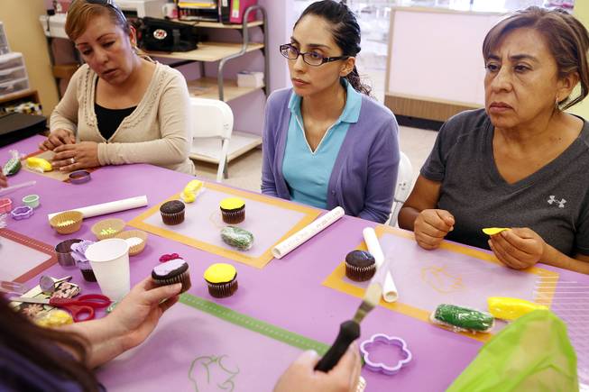 Eva Ibarrola, from left, Rocio Quezada and Maria Lourdes Ibarra listen as Nilda Arias teaches a class in Spanish on cupcake decorating at Sweet House in Las Vegas on Monday, September 223, 2013.